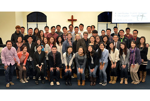 Members of Sugarloaf International Fellowship (SIF) surround their pastor, Jim Burton, center, and his wife, Kim, and their son, Jacob, on Nov. 17, 2013, during the last month of his tenure there. The congregation was primarily English-speaking Korean millennials. Burton resigned due to failing health following his ALS (Lou Gherig's Disease) diagnosis. (Photo by Yusung Park)