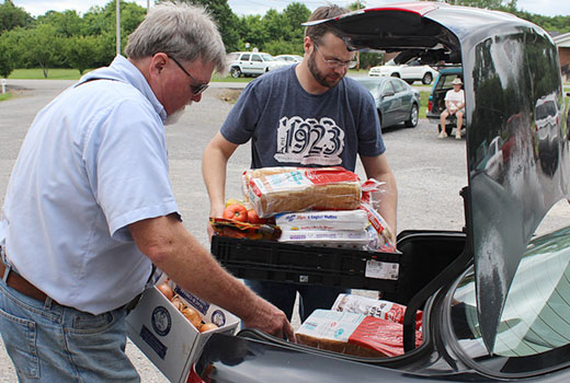 Doug Mitchell (left), pastor of Midland Baptist Church in rural Tennessee, and Roger Brown of Cedar Grove United Methodist Church, load food into the car of a family receiving aid at Midland's Journey of Hope Ministry Center. (Photo by Lonnie Wilkey)