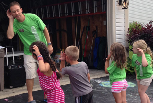 William Lawler, worship pastor at Violet Baptist Church, leads an upbeat song and motions during a neighborhood backyard Bible club.