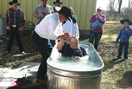 Idaho cowboy church planter and pastor David Kite baptizes a new believer in a horse trough.