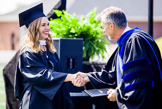 NGU interim president Randall Pannell congratulates a 2016 graduate at commencement.