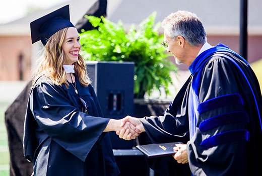 NGU interim president Randall Pannell congratulates a 2016 graduate at commencement. 