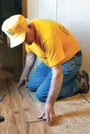 A disaster relief volunteer installs new flooring for a South Carolina homeowner.