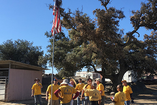 California DR volunteers gather with Bill Cronkrite at his property under an American flag that survived this summer’s Border Fire in San Diego County. (Submitted photo)