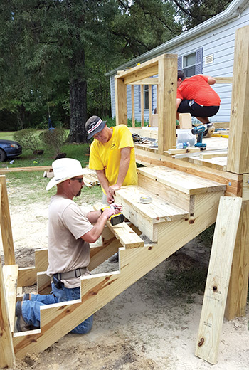 Volunteers build stairs for a new deck.